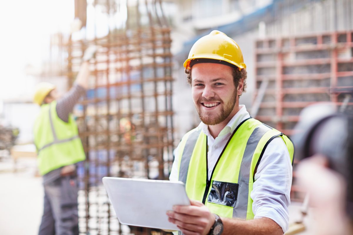 Portrait confident construction worker digital tablet at constru