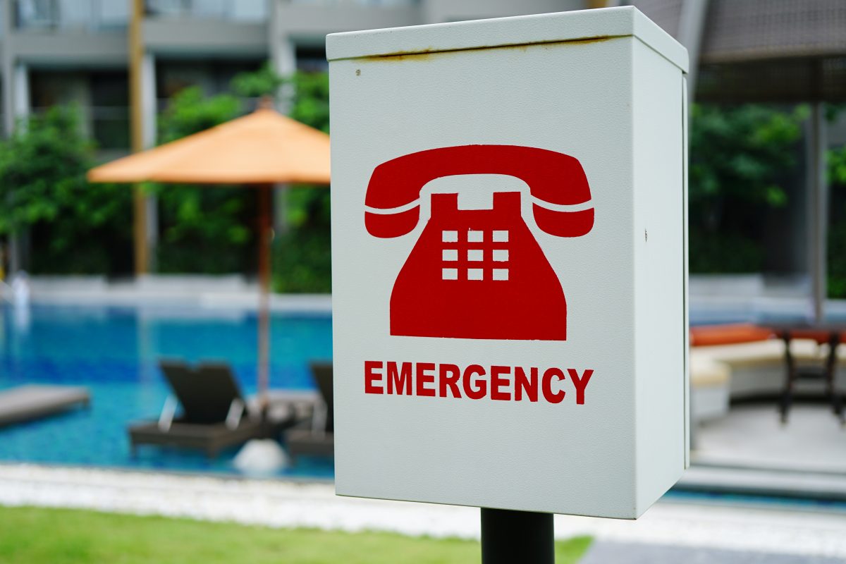 The red emergency phone box beside a hotel hospitality swimming pool