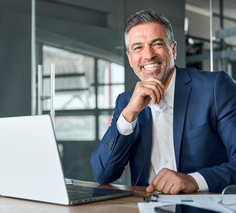 Happy middle aged business man ceo working on laptop sitting in office.