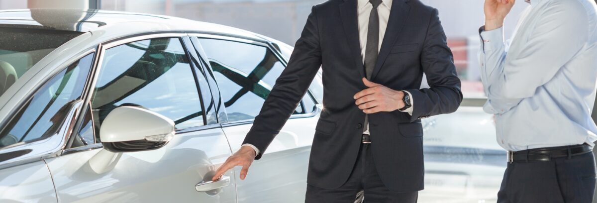 Young man in suit standing by his modern luxurious car