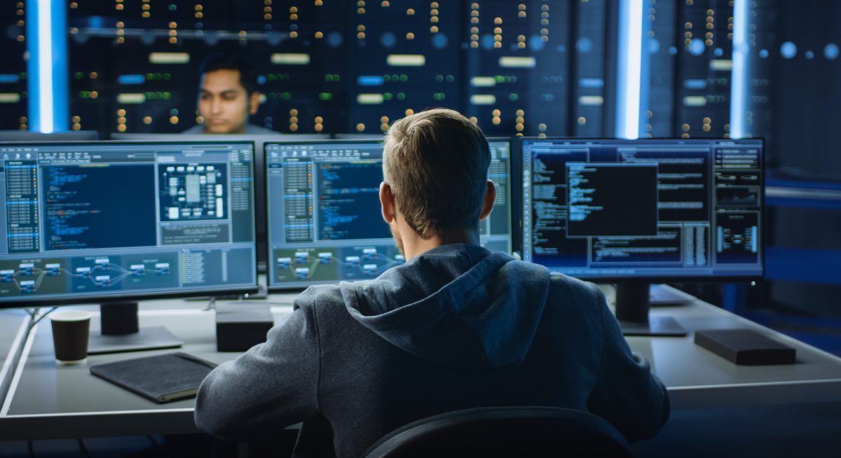IT Specialist Works on Computer with Screens Showing data